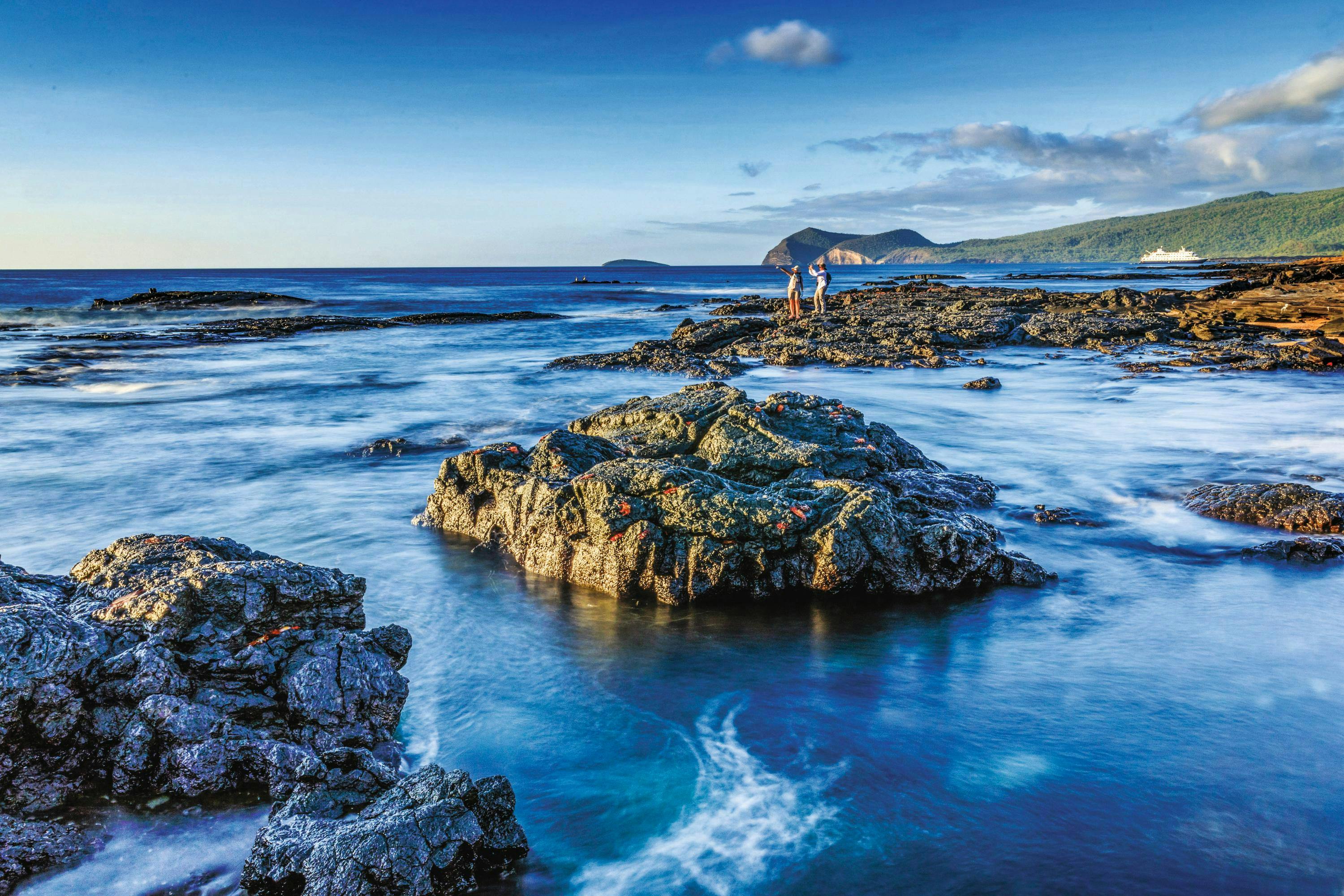 Photographers at sunset, rocky shore, Santiago Island, Lava Rocks, Water Motion, Island, Galapagos Islands, Galapagos National Park, Ecuador.