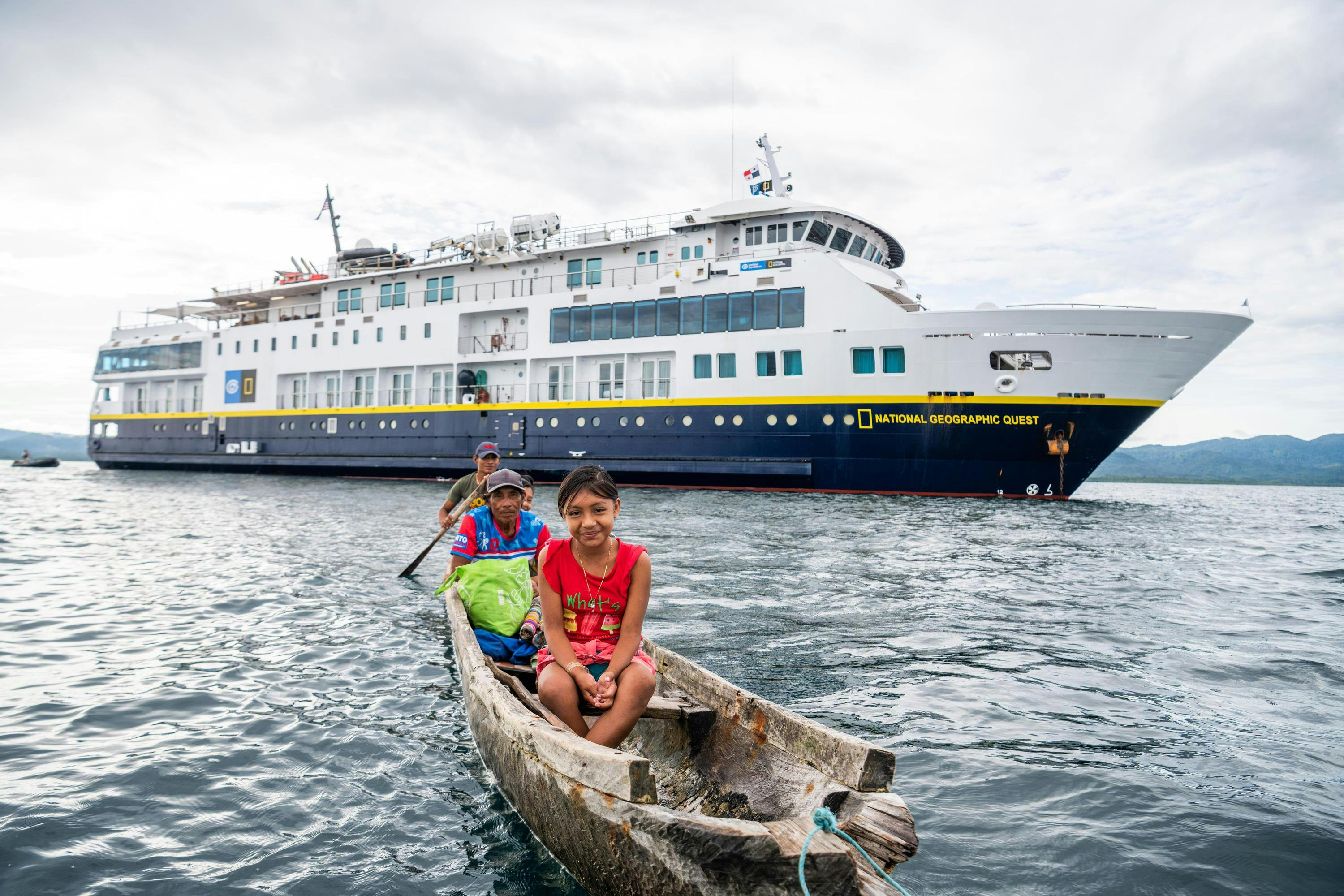 A family of local villagers in a handmade wooden canoe by the ship National Geographic Quest in Guna Yala, Panama